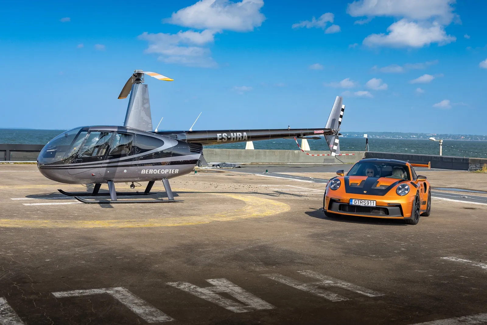 Helikopter ja sportauto mereäärsel maandumisplatsil